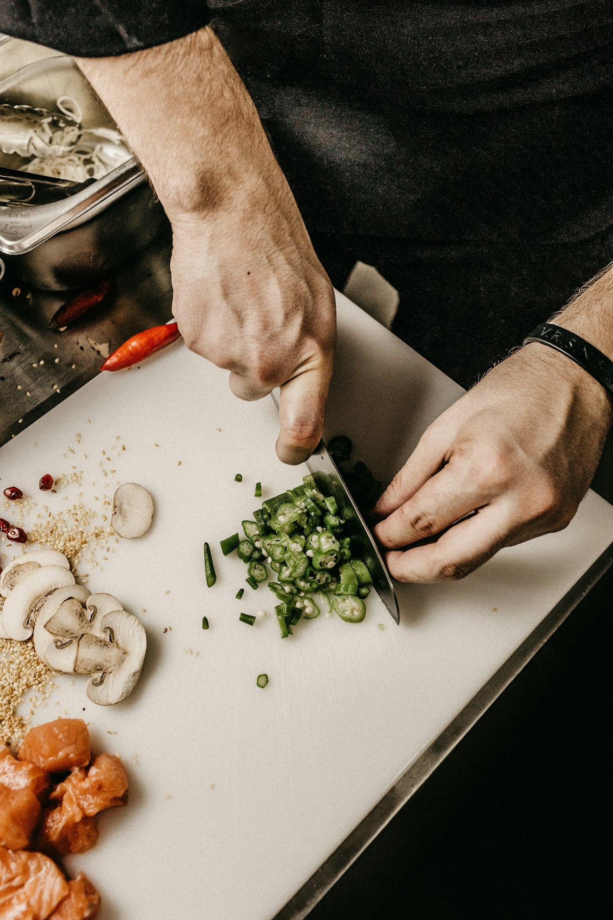 Chef's hands chopping fresh greens on a board