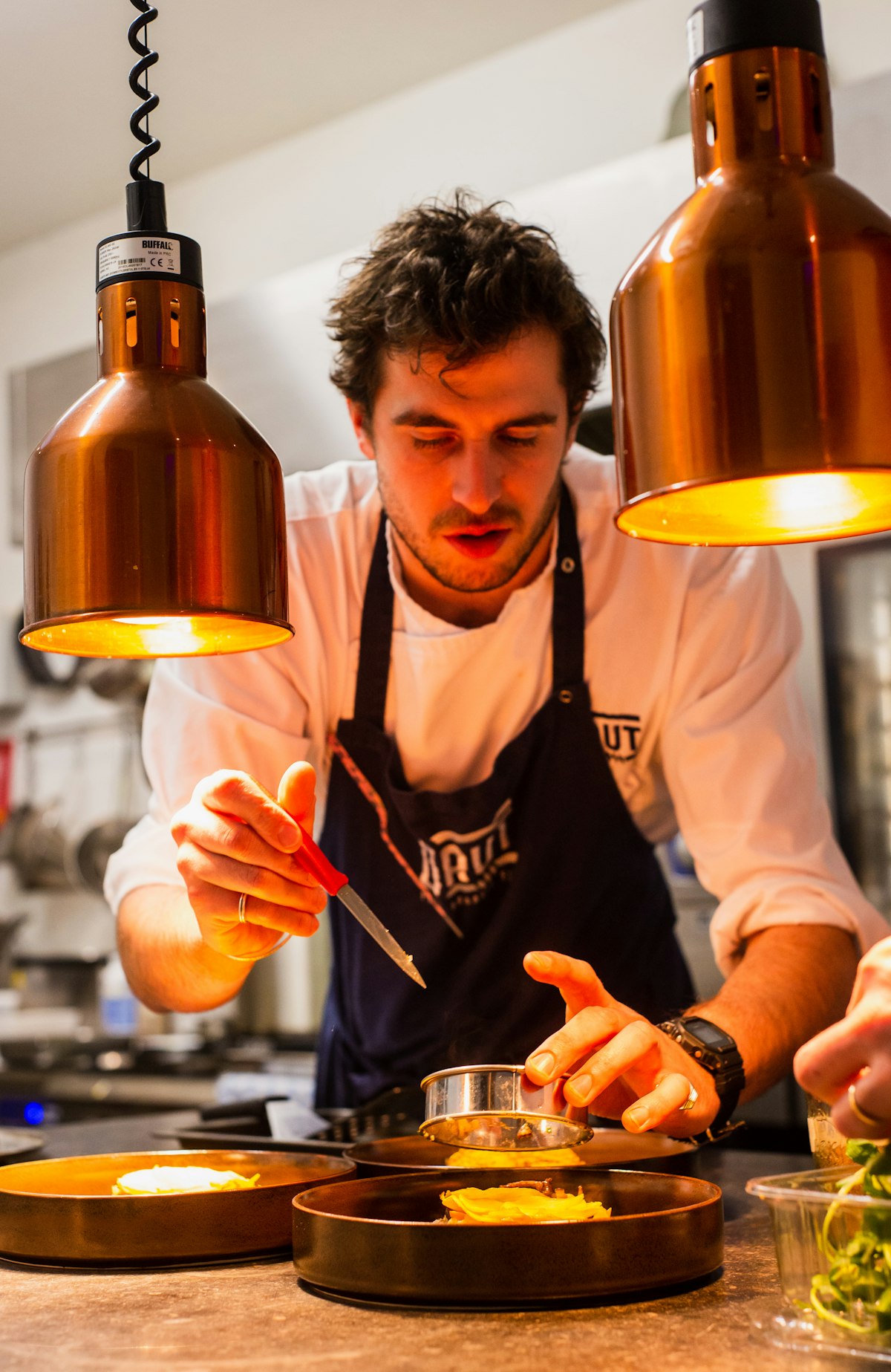 Chef plating dishes under warm heat lamps