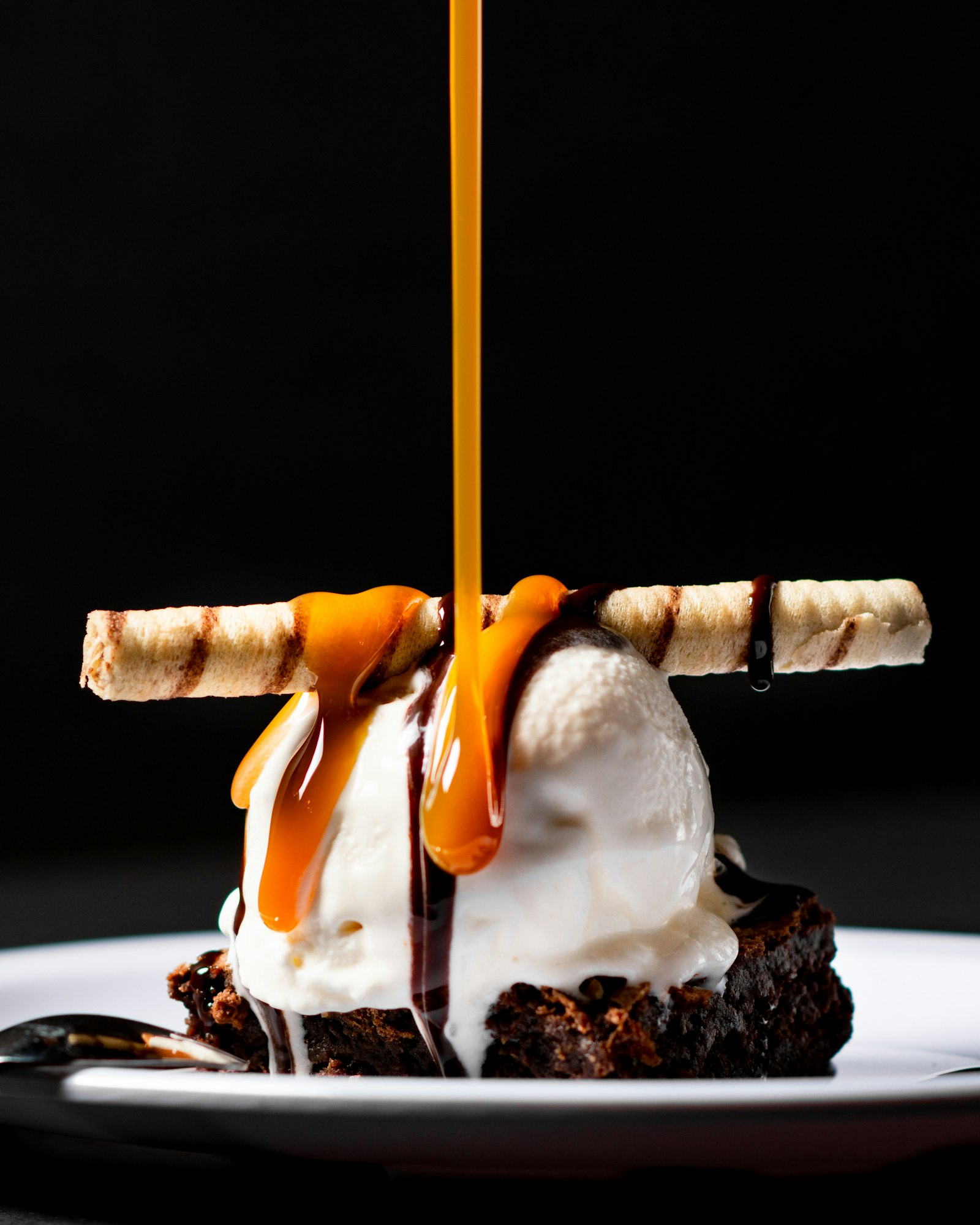 Brownie sundae with caramel pour on a black background