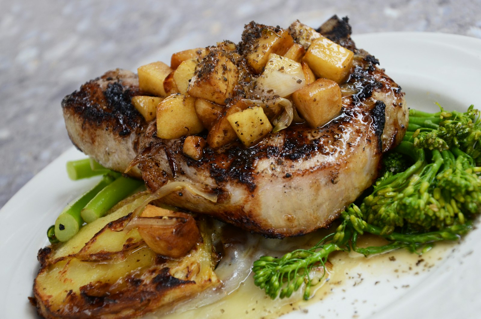 Plated grilled pork chop with apple chutney and broccolini